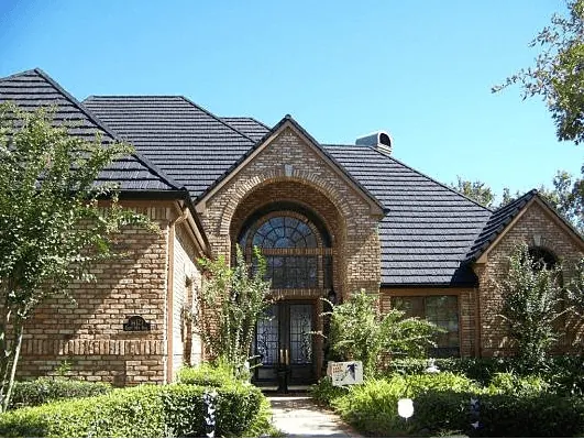 Brick home with a dark stone-coated metal roof and an arched front entry