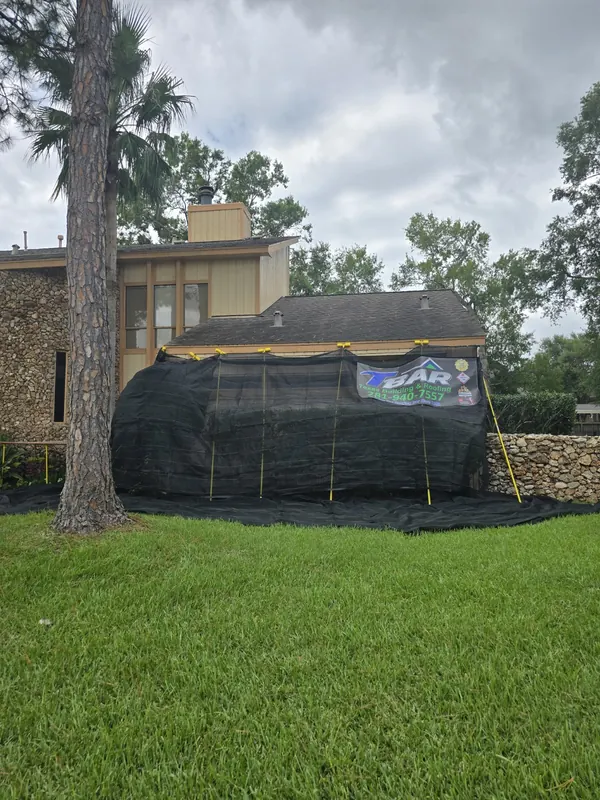 Protective netting and ground covering set around landscaping beside a home